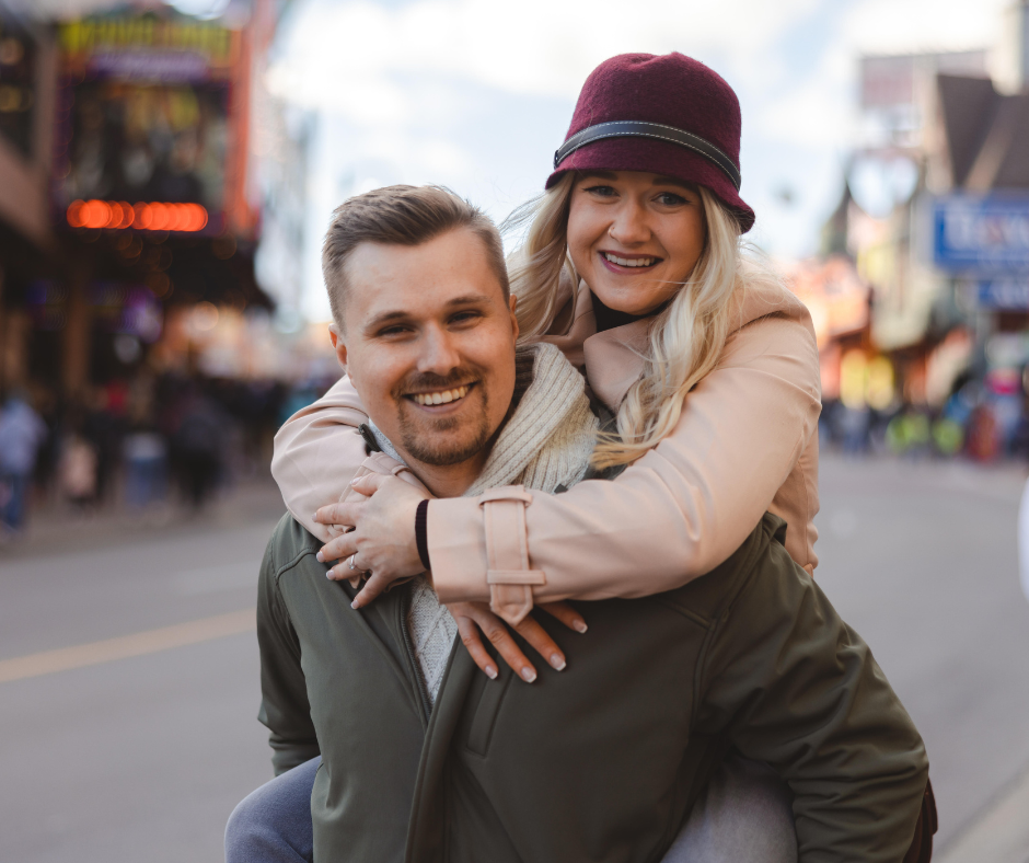 Billy Morrison and Katherine Murphy enjoying a day on Clifton Hill in Niagara Falls during their surprise engagement photoshoot. Katherine is on Billy's back with her arms around him. They are both extremely happy.