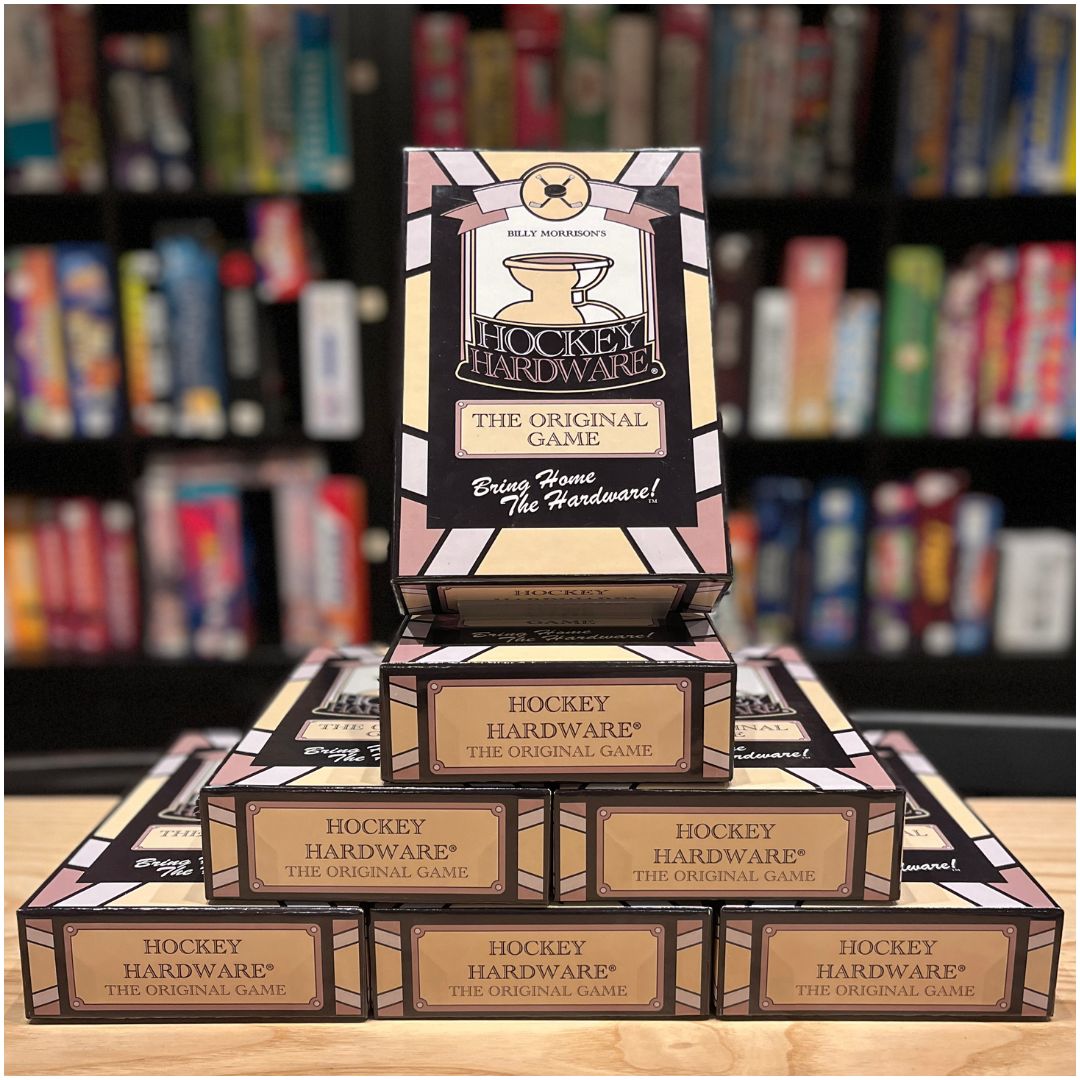 Hockey Hardware games stacked on top of each other in the shape of a pyramid, positioned in front of a colourful bookcase of games.