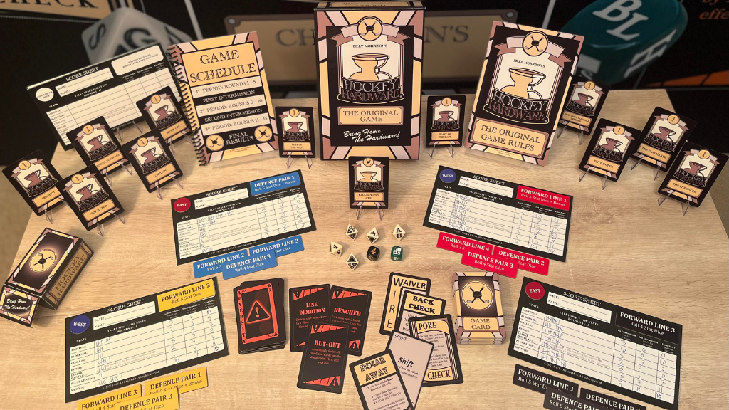 A collection of Hockey Hardware tabletop game components on display, including cards, dice, score sheets, and a game box on a wooden surface.